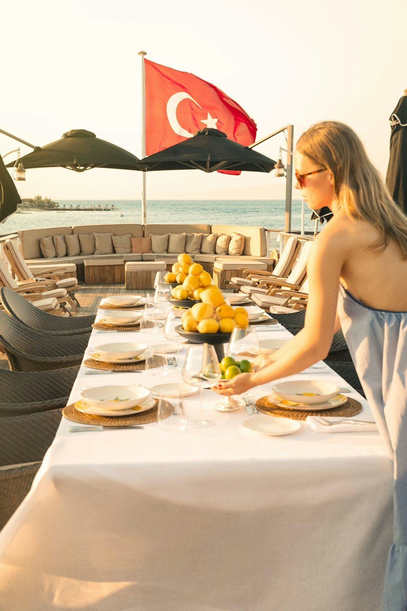 a woman sitting at a table with food and drinks on it aboard HALAS 71 Yacht for Charter
