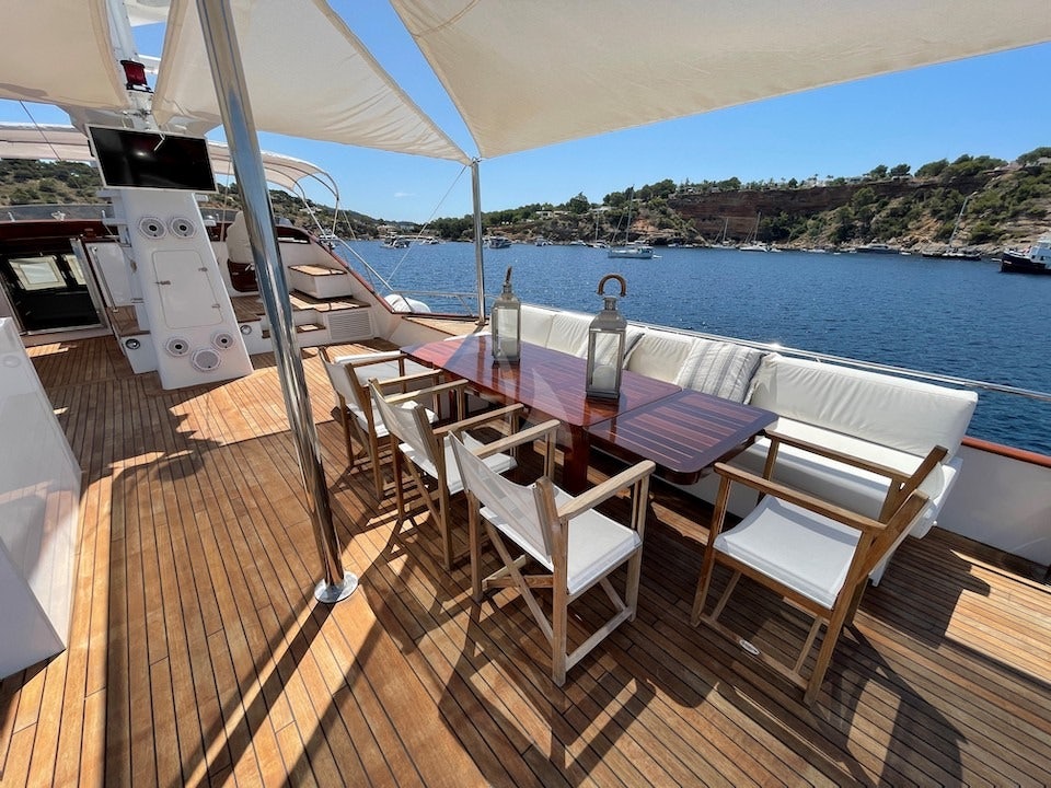 a deck with a table and chairs on it aboard SPIRIT OF MK Yacht for Charter