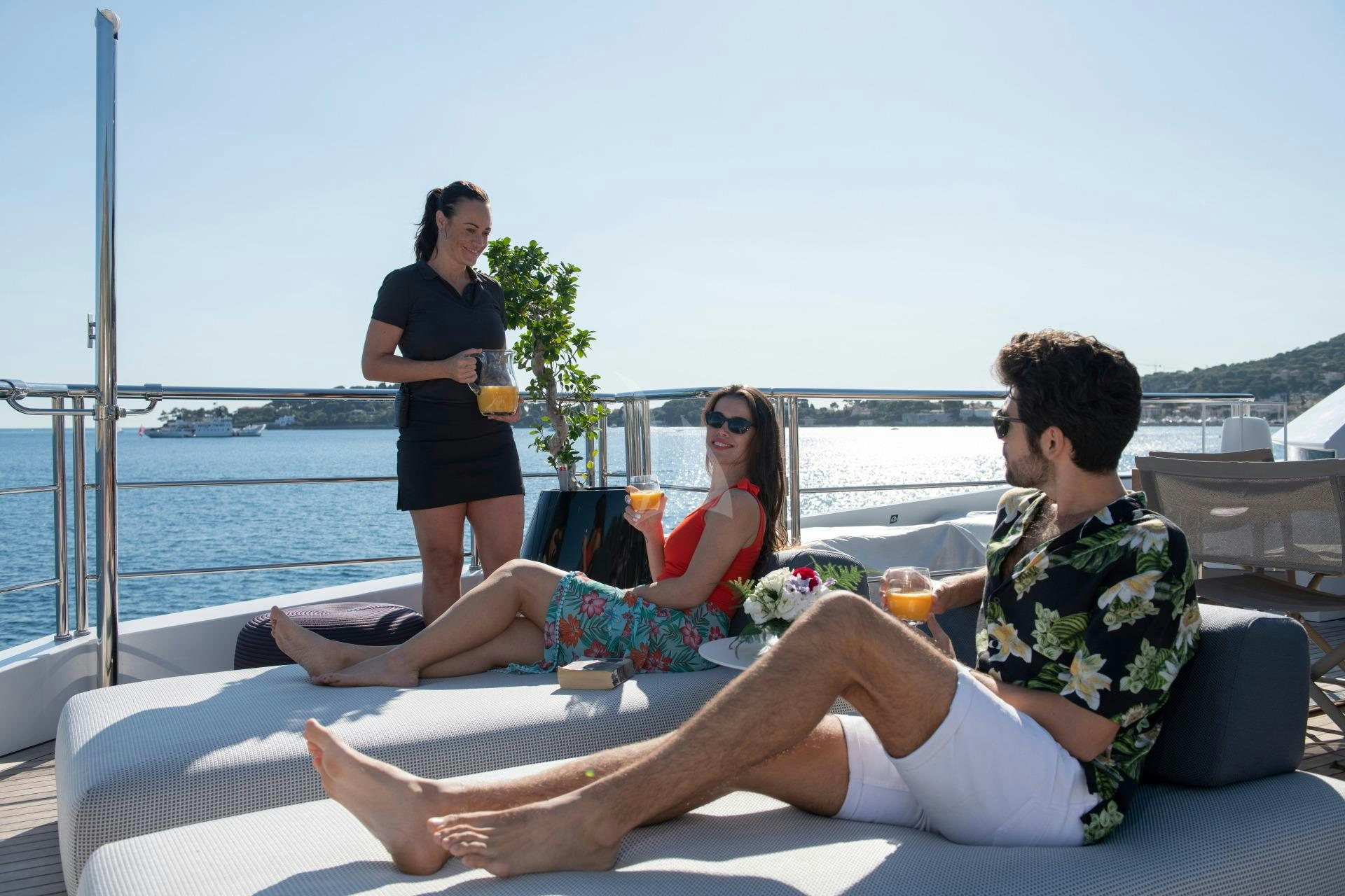 a group of people sitting on a couch on a beach aboard NEXT Yacht for Charter
