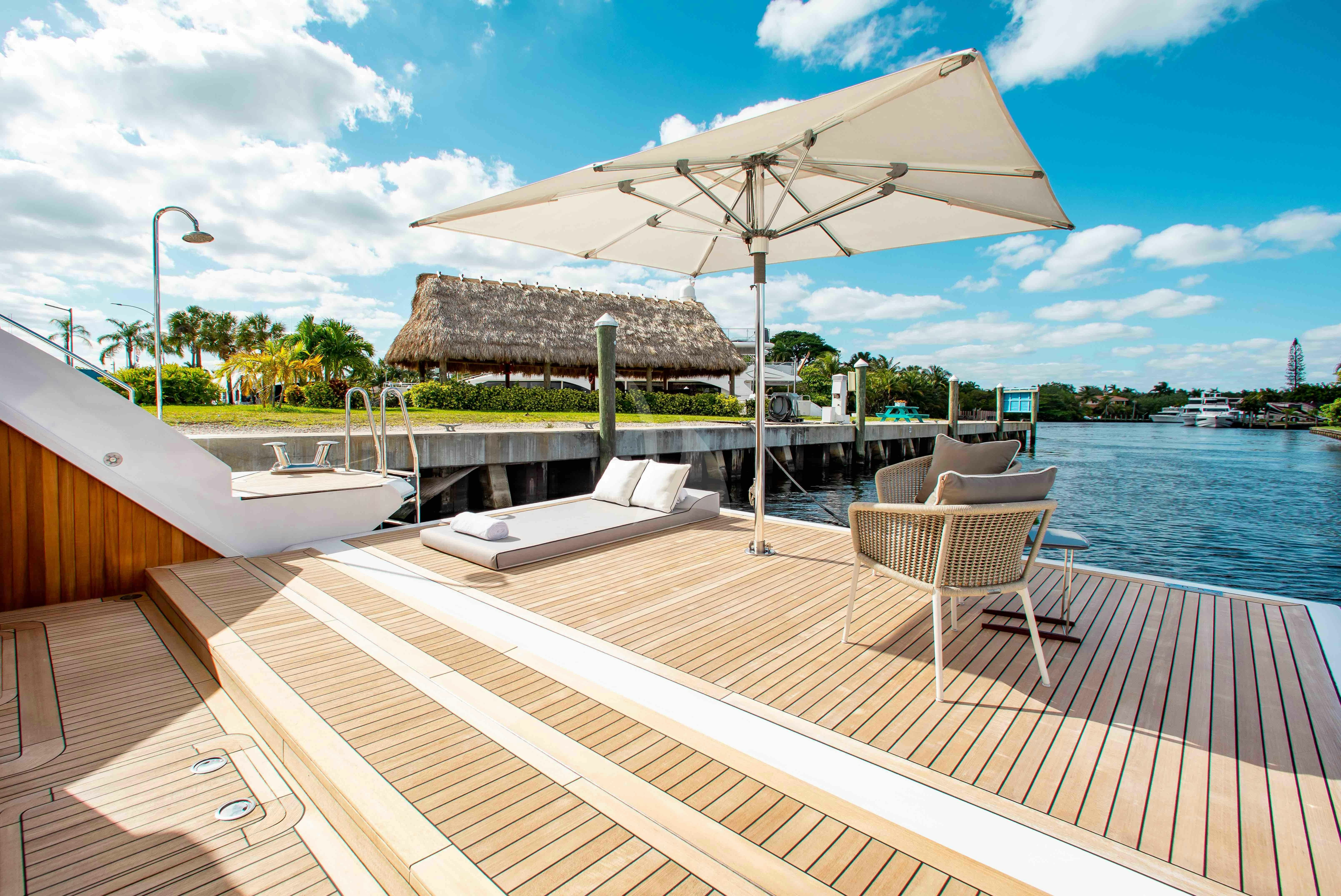 a deck with chairs and an umbrella aboard EMINA Yacht for Charter