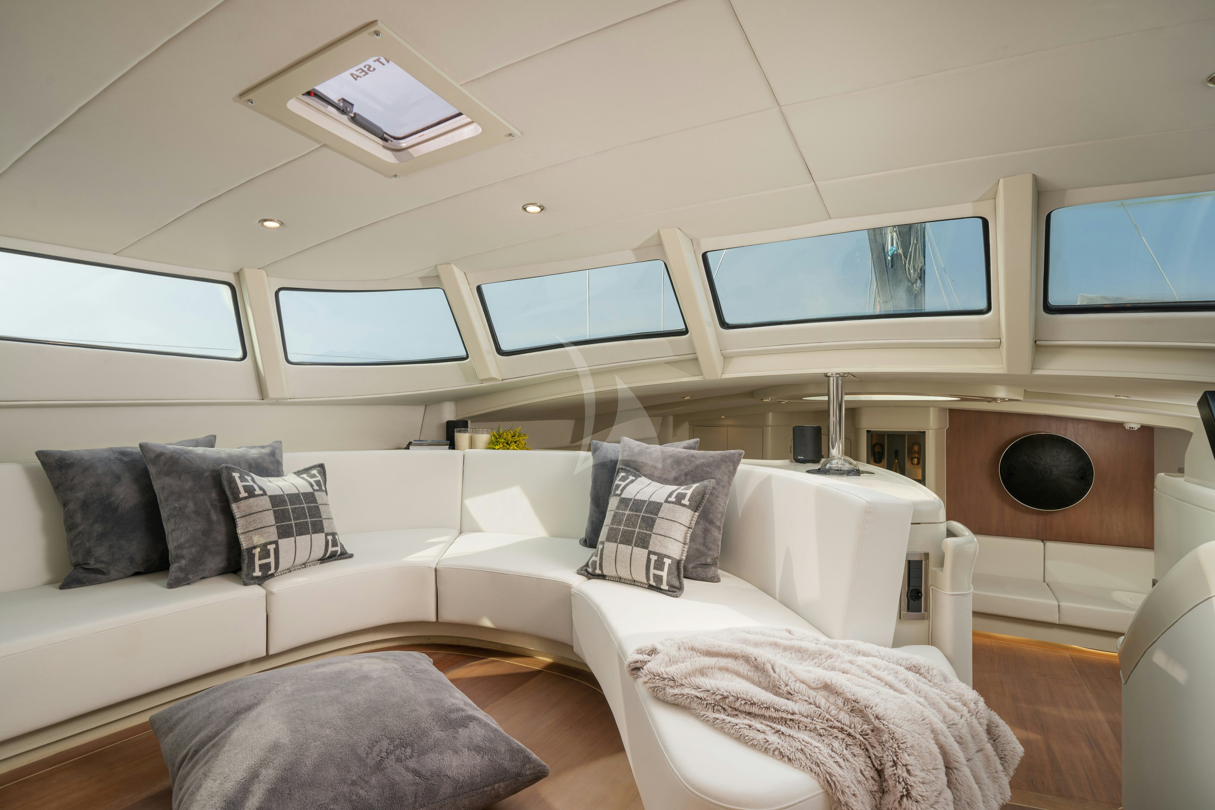 a white couch with pillows and a television in a room with a wood floor and white walls and aboard ASHLEYROSE110 Yacht for Charter