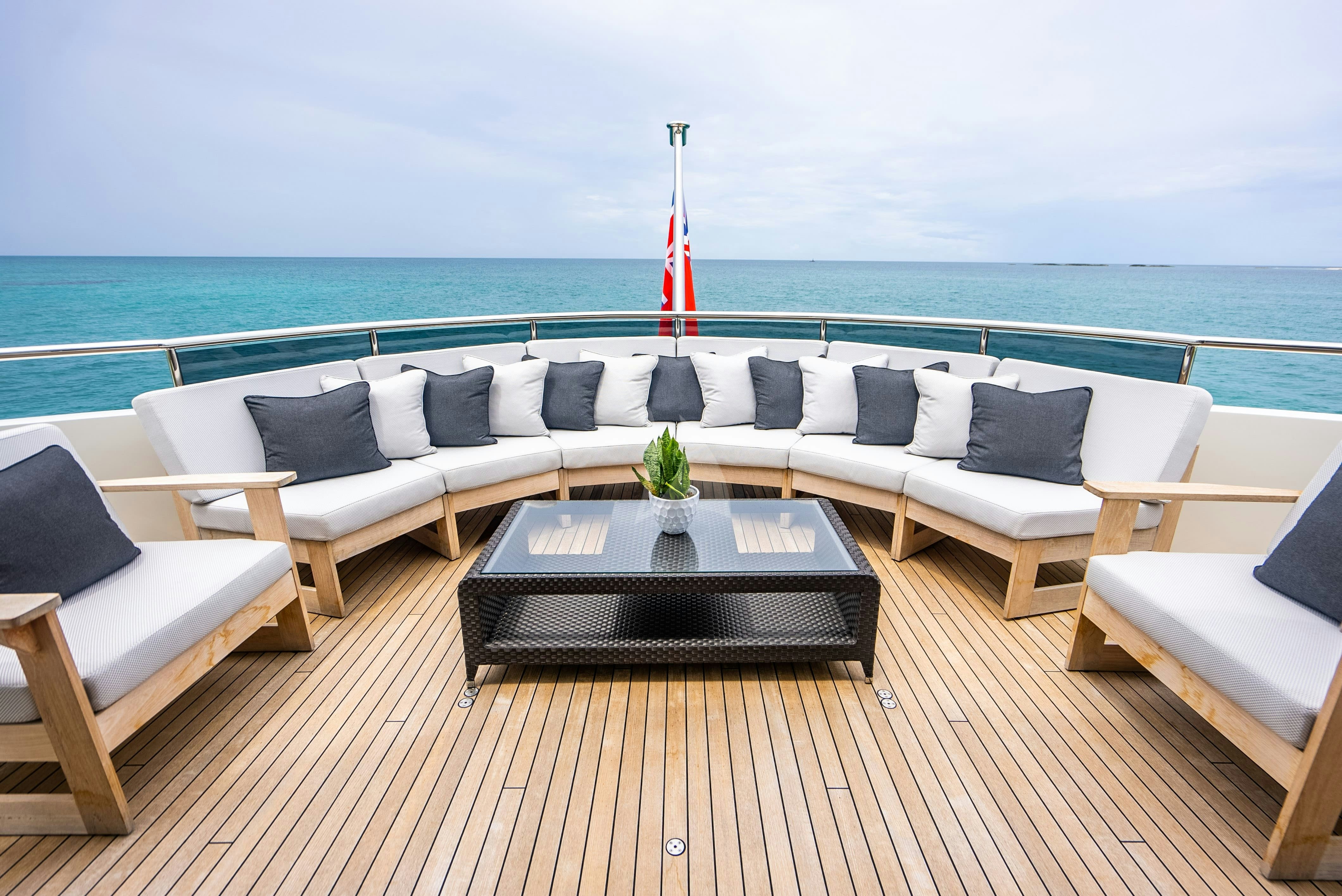 a couch and a table on a deck overlooking a beach aboard ODYSSEA Yacht for Charter