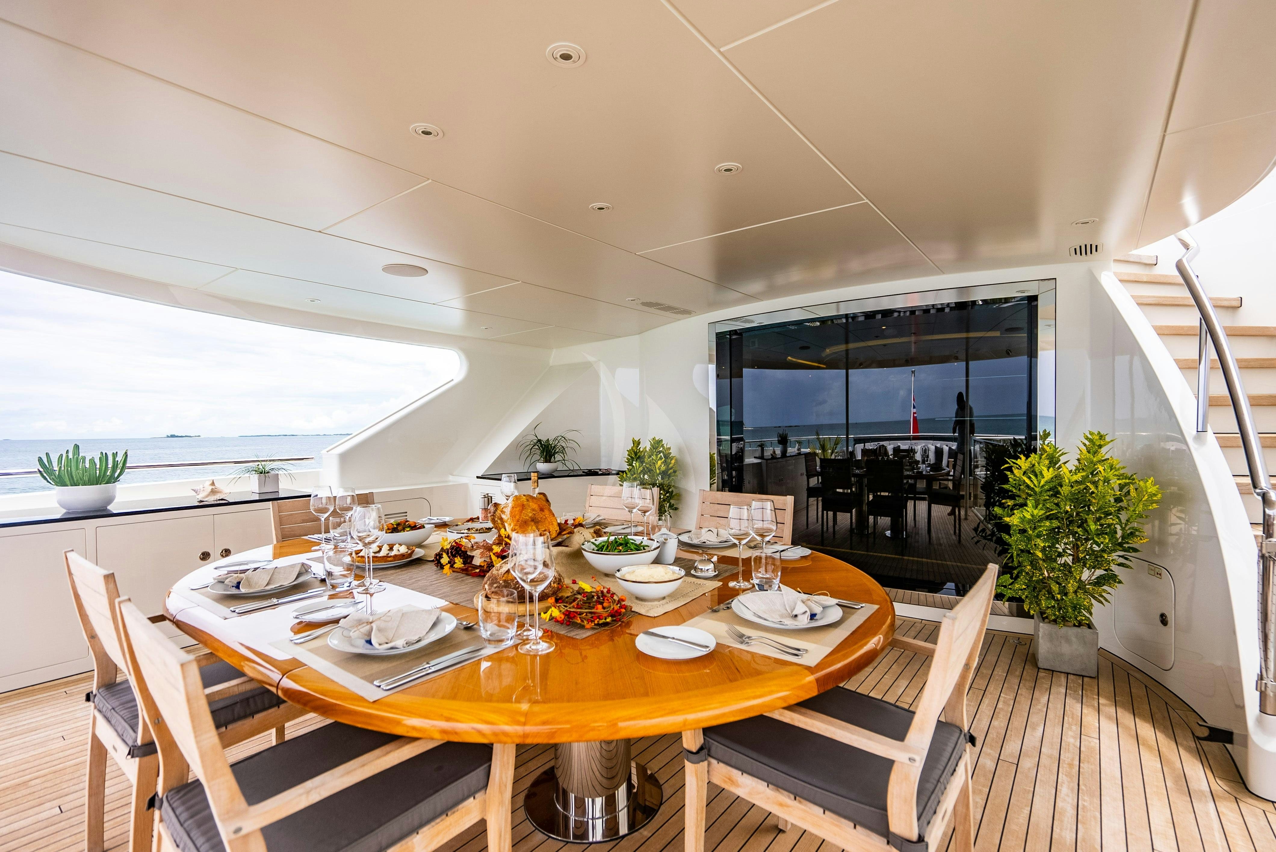 a dining table with chairs and a view of the ocean aboard ODYSSEA Yacht for Charter