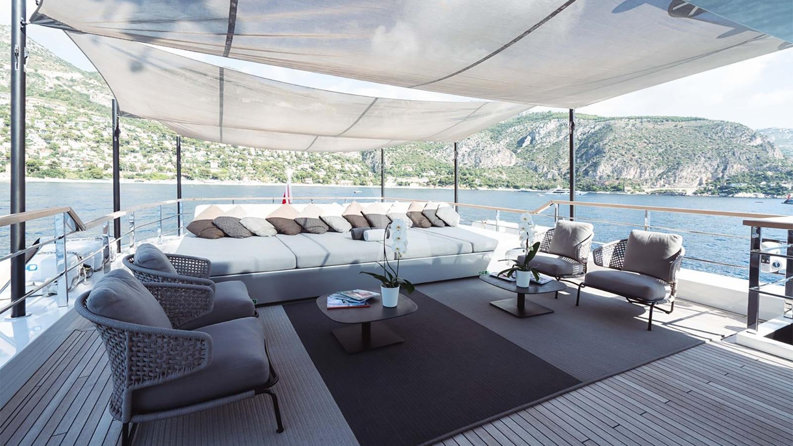 a large white couch and chairs on a deck overlooking a large body of water aboard JESMA II Yacht for Charter