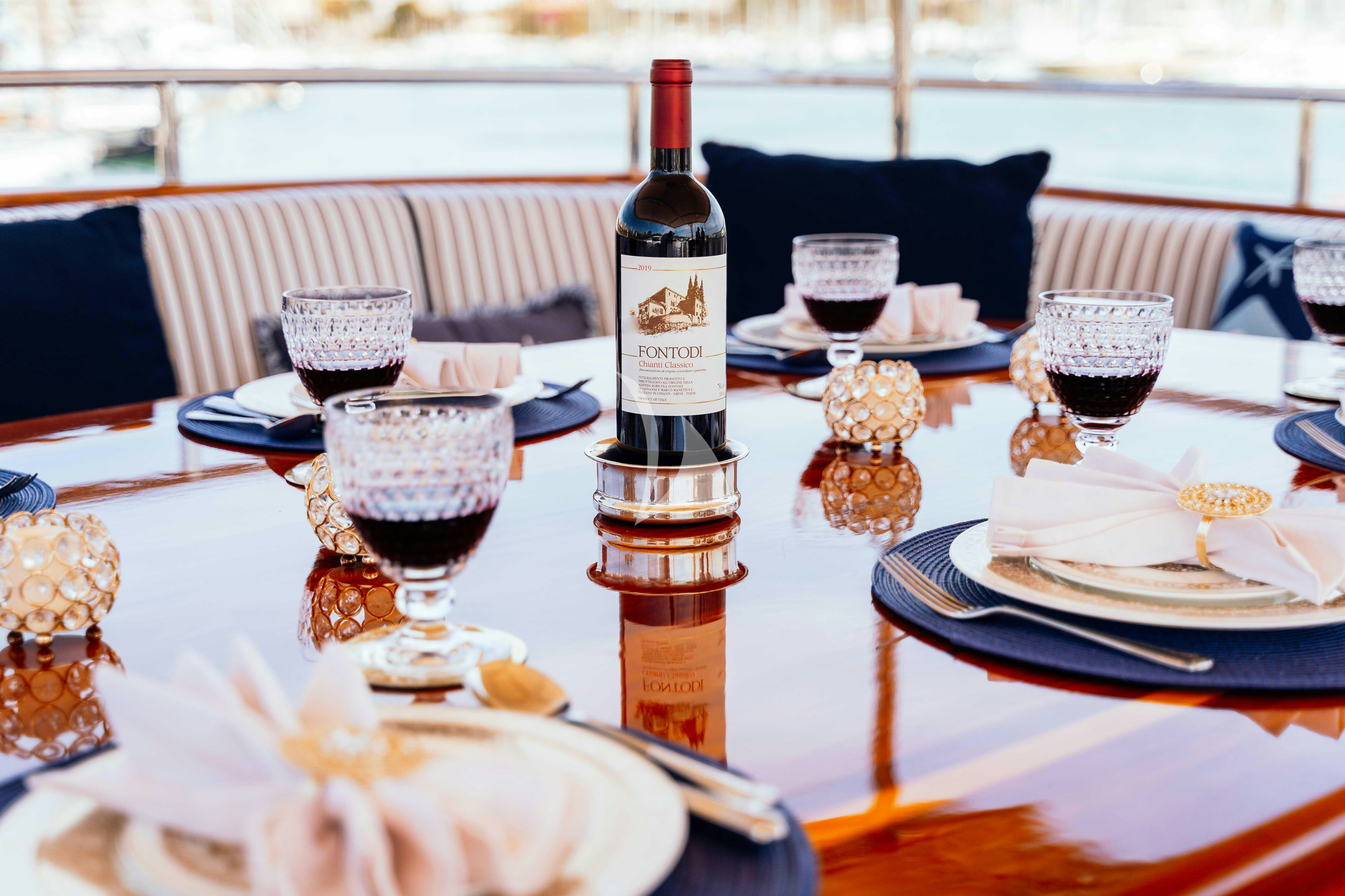 a table with plates and wine bottles aboard ODYSSEY III Yacht for Charter