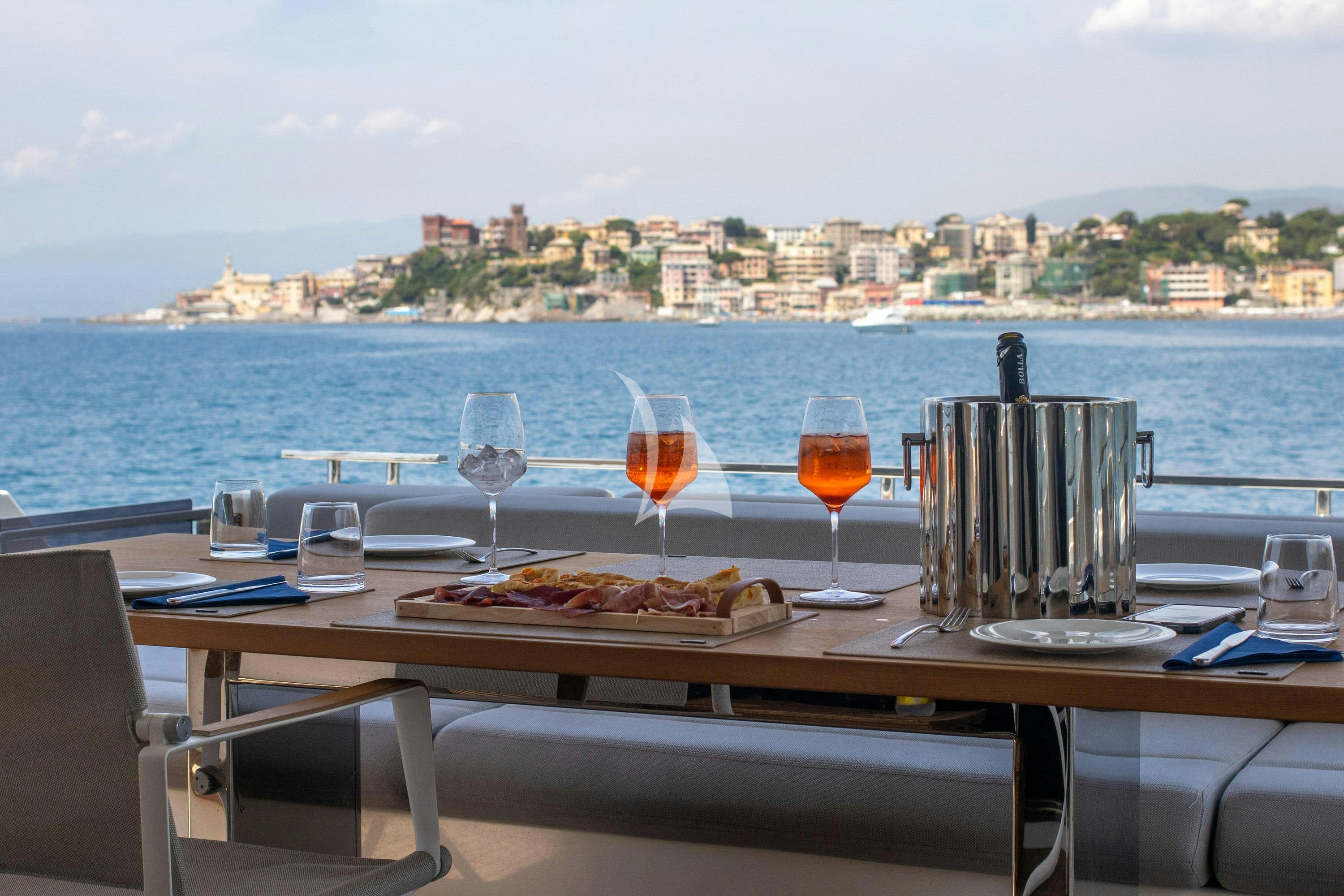a table with food and glasses on it by a window with a view of a city and water aboard E3 Yacht for Charter