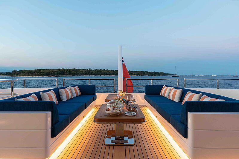 a balcony with a table and a couch and a boat on the water aboard SOARING Yacht for Charter