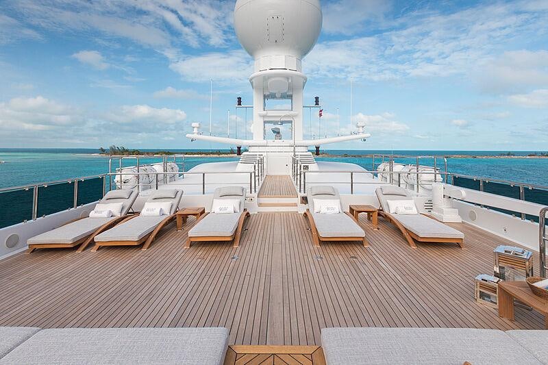 a deck with a deck and chairs on it and a body of water in the background aboard JOIA THE CROWN JEWEL Yacht for Charter
