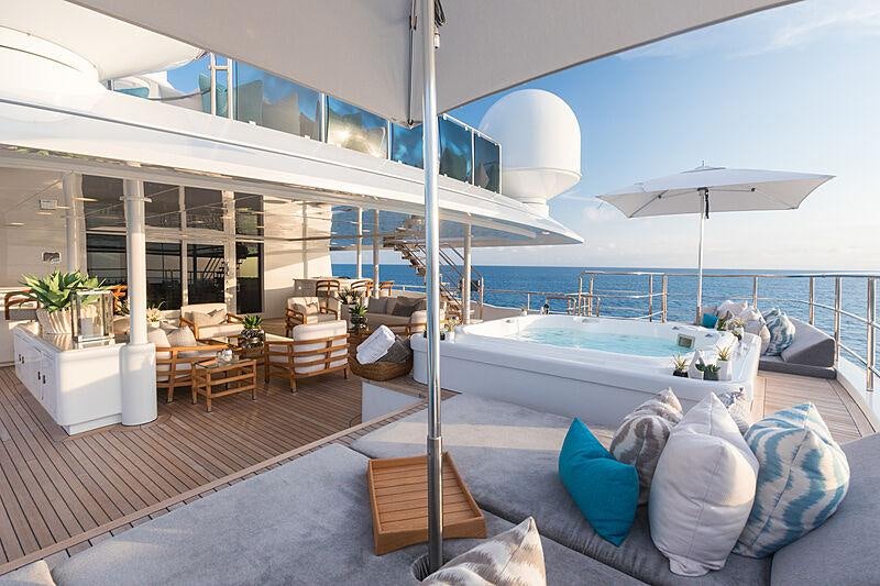 a large lounge area with a large lounge chair and a large pool aboard JOIA THE CROWN JEWEL Yacht for Charter