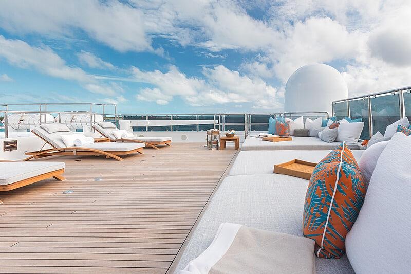 a deck with a view of the ocean and a large white building aboard JOIA THE CROWN JEWEL Yacht for Charter
