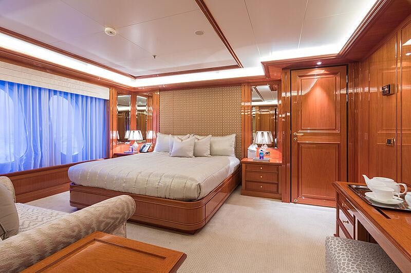 a bedroom with a bed and a table aboard JOIA THE CROWN JEWEL Yacht for Charter