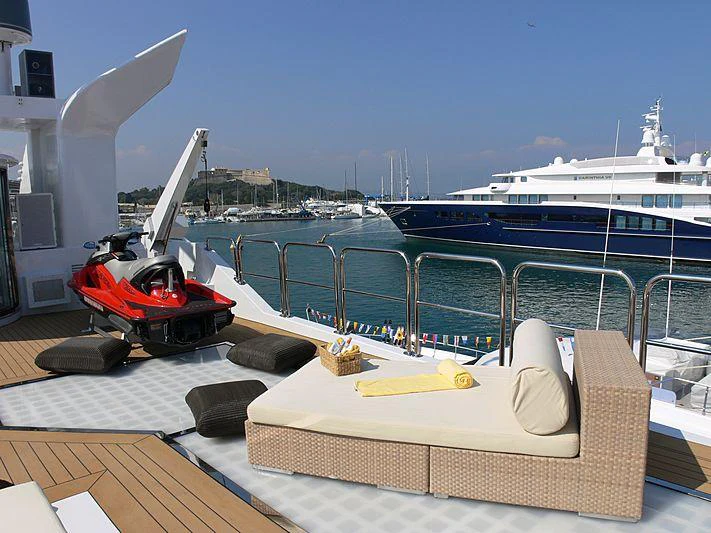 a deck with a chair and a boat in the background aboard MAGNA GRECIA Yacht for Charter