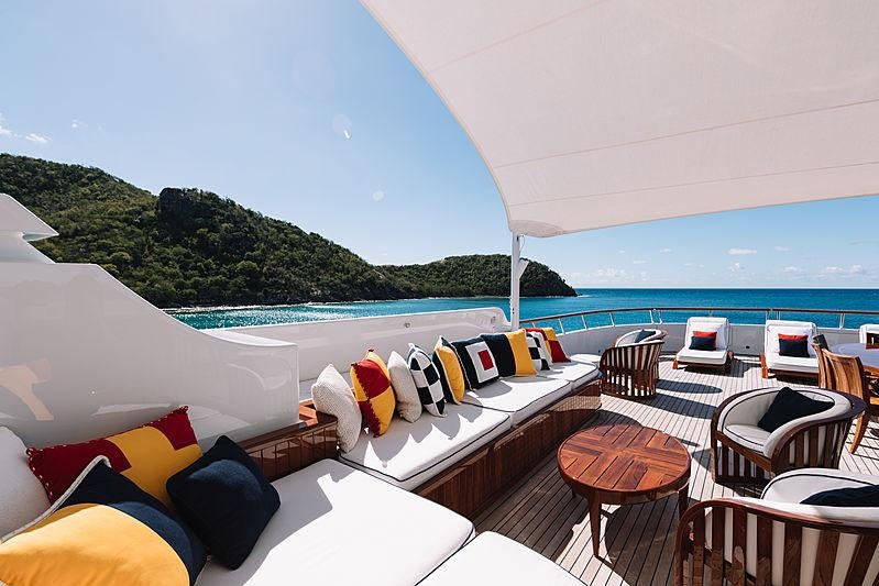 a room with a pool and a deck with chairs and tables aboard FLAG Yacht for Charter