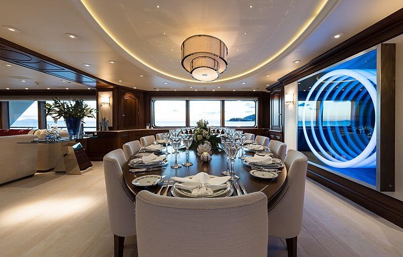 a dining room with a large blue round table and chairs aboard FLAG Yacht for Charter