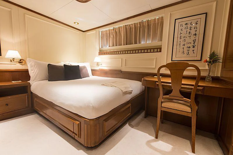 a bed with a white bed and a chair next to it aboard SEAWOLF Yacht for Charter