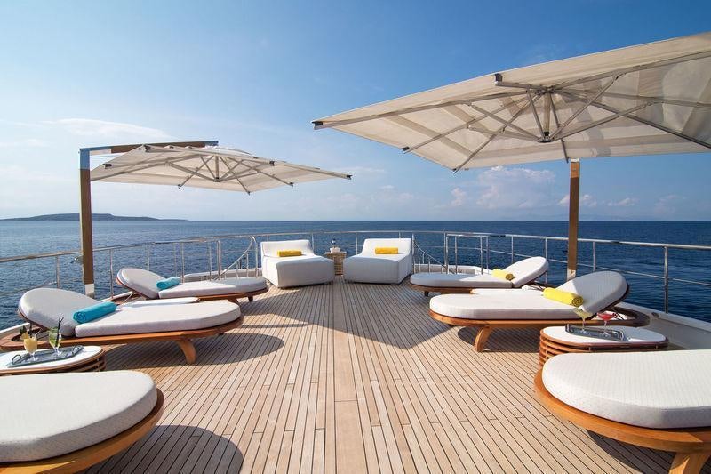 a deck with lounge chairs and a large umbrella on it aboard O'NATALINA Yacht for Charter