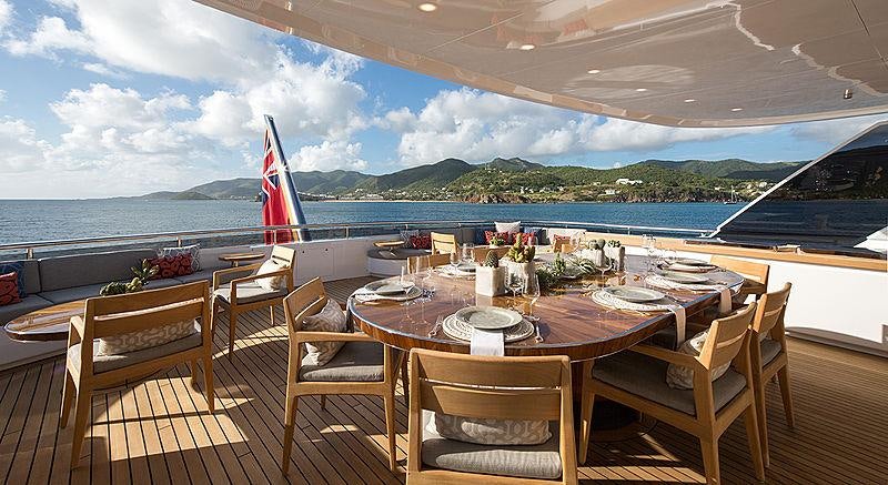 a table set for a meal on a deck overlooking a large body of water aboard REVERIE Yacht for Charter