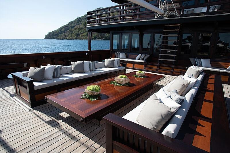 a deck with a couch and a table on it aboard DUNIA BARU Yacht for Charter