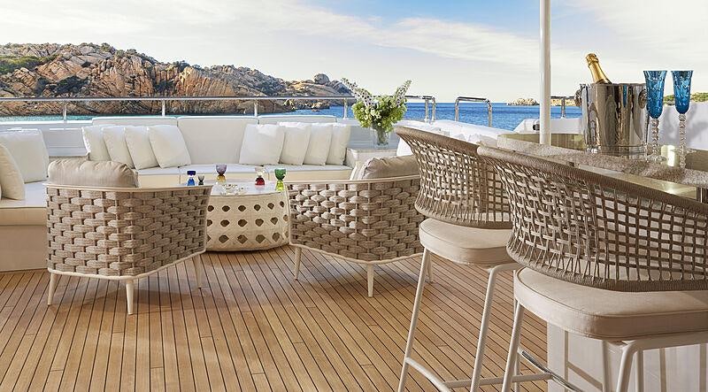 a table and chairs on a deck overlooking a body of water aboard ARKADIA Yacht for Charter