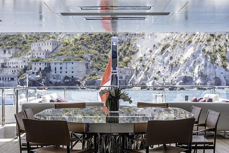 a room with a table and chairs and a view of a city aboard LEL Yacht for Charter