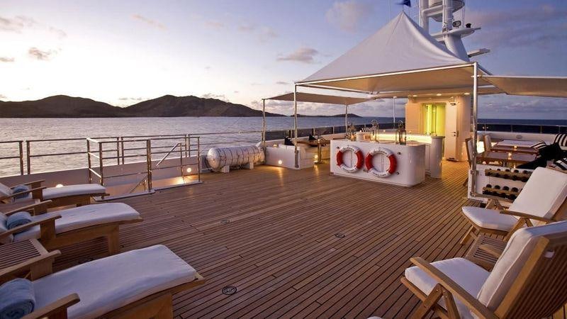 a deck with a boat and chairs on it aboard TE MANU Yacht for Charter