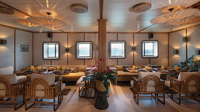 a room with a large screen and tables and chairs aboard KUDANIL EXPLORER Yacht for Charter