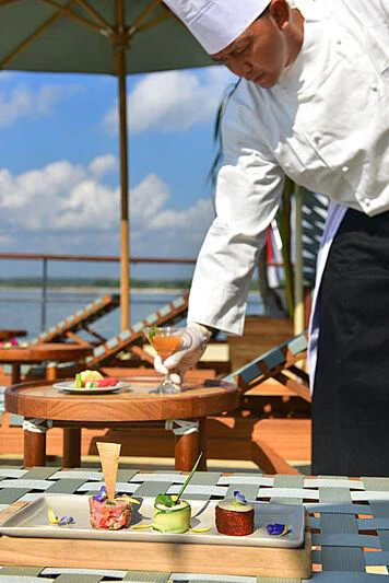 a man pouring a drink into a glass on a table aboard KUDANIL EXPLORER Yacht for Charter