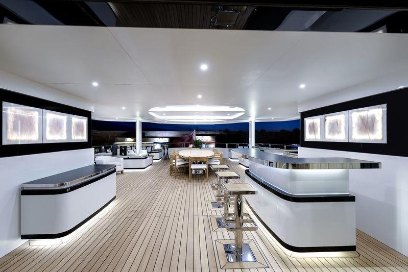 a room with a table chairs and a large screen aboard LIQUID SKY Yacht for Charter