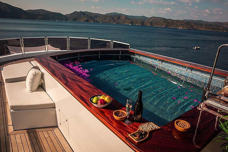 a deck with a large pool and a view of the ocean aboard OCEAN BREEZE Yacht for Charter