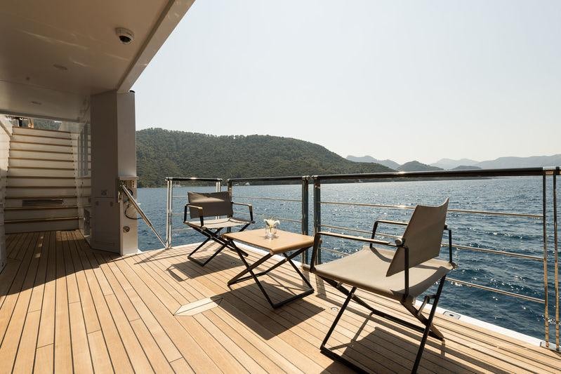 a deck with a table and chairs on it aboard AQUARIUS Yacht for Charter