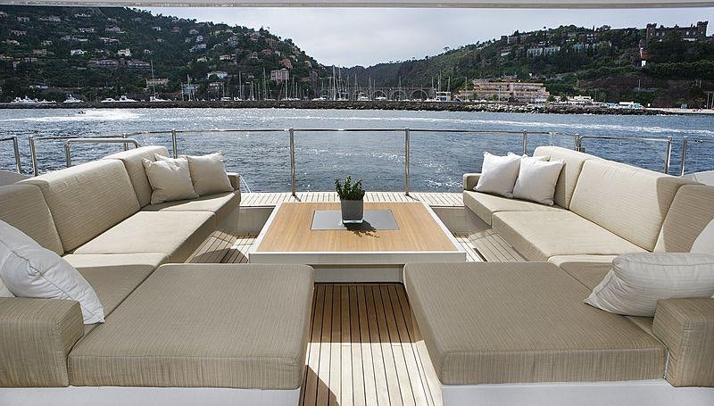 a room with a table and couches by a body of water aboard LAMMOUCHE Yacht for Charter