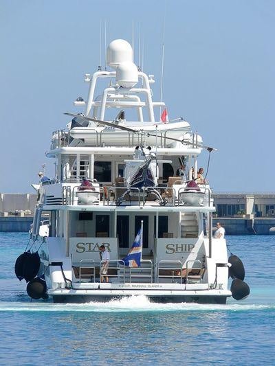 a large white boat with a flag on it aboard STARSHIP Yacht for Charter