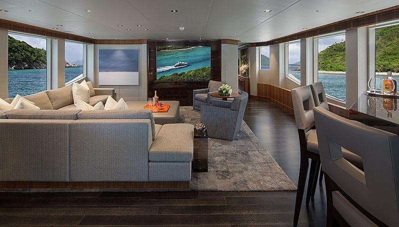 a living room with a large sofa and a large window aboard MUCHOS MAS Yacht for Charter