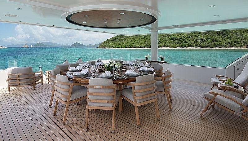 a table and chairs on a deck overlooking a body of water aboard MUCHOS MAS Yacht for Charter
