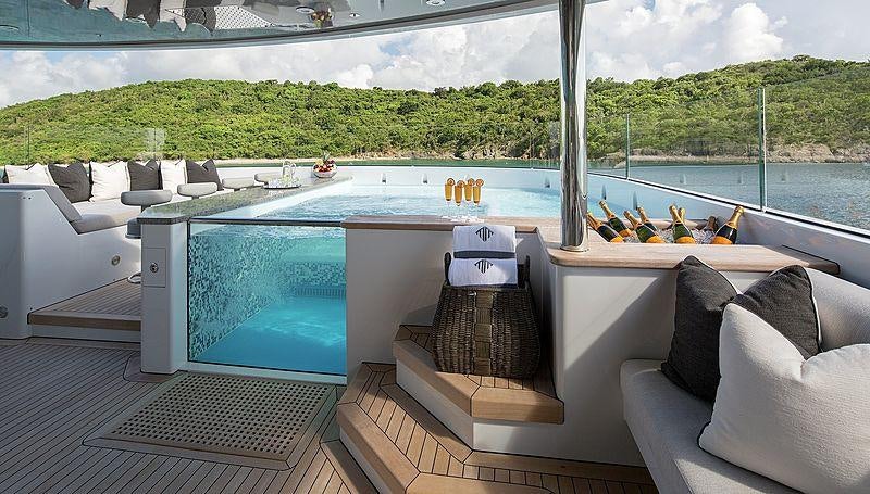 a room with a large pool and a deck with a large deck aboard MUCHOS MAS Yacht for Charter