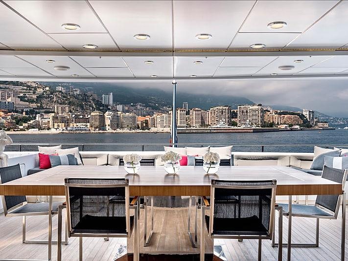 a table with chairs and a view of a city aboard THANUJA Yacht for Charter