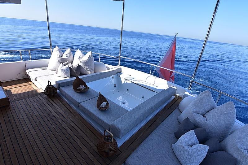 a deck with a large white bed and a red flag on it aboard LIFE SAGA Yacht for Charter