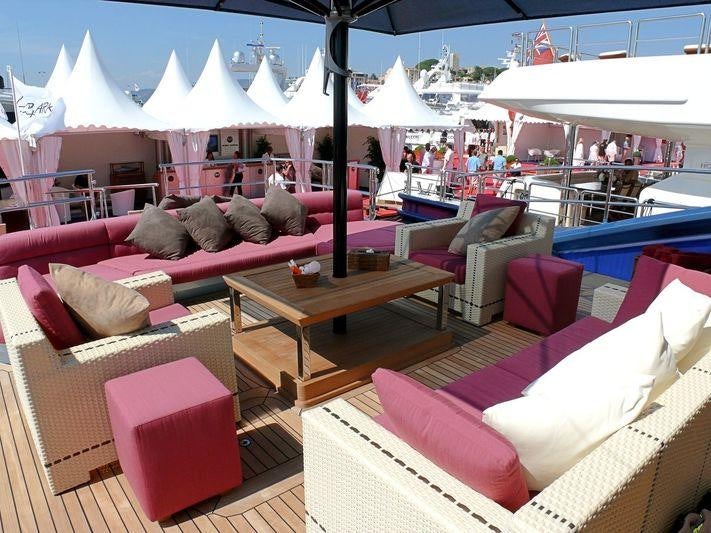 a group of pink couches and a table with a tent in the background aboard WAVERUNNER Yacht for Charter