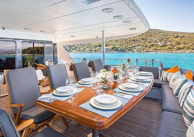a table set for a meal on a deck overlooking a large body of water aboard BRAZIL Yacht for Charter