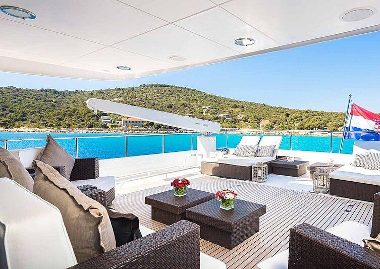 a room with a pool and a deck with chairs and a table aboard BRAZIL Yacht for Charter