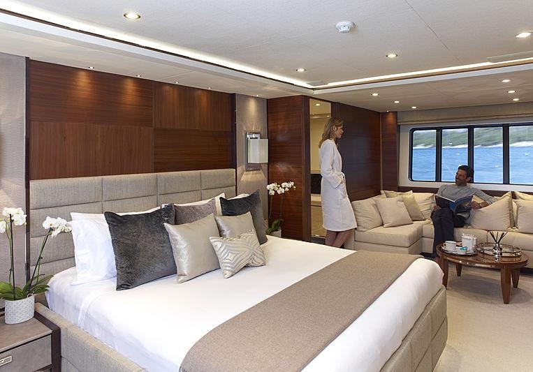 a man and woman standing in a room with a large white bed aboard IMPERIAL PRINCESS BEATRICE Yacht for Charter