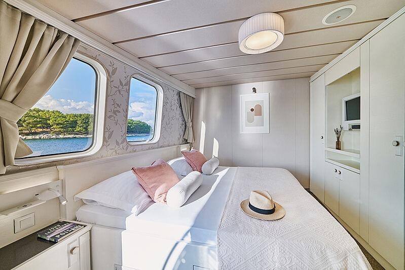 a bedroom with a bed and a window aboard LA PERLA Yacht for Charter