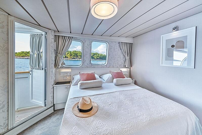 a bed with a white bed spread aboard LA PERLA Yacht for Charter