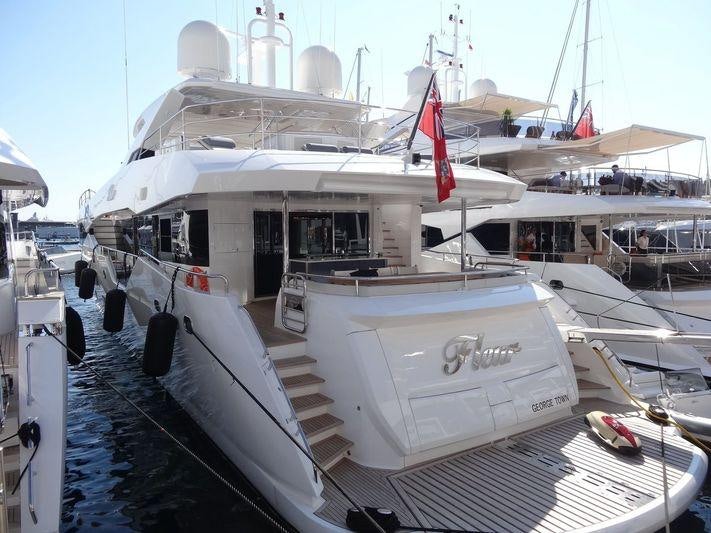 a large white boat with a red and white stripe on the front aboard FLEUR Yacht for Charter