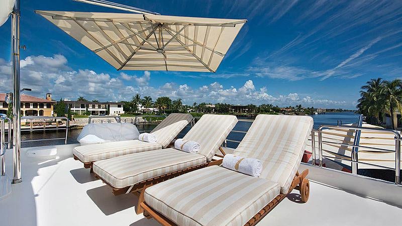 a lounge area with lounge chairs and an umbrella aboard FRIENDSHIP Yacht for Charter