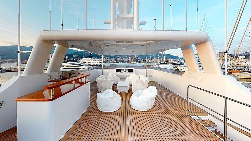 a deck with a view of the water and a large ship aboard ATOM Yacht for Charter