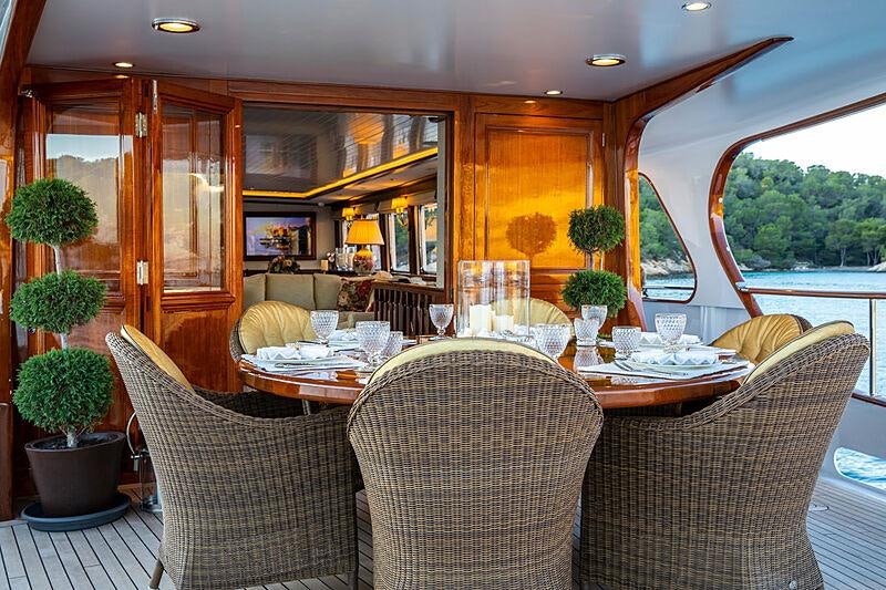 a dining table and chairs in a room with a window aboard ODYSSEY III Yacht for Charter