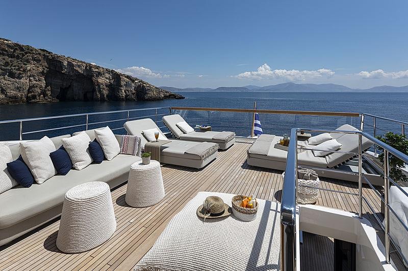 a large white table with chairs and a large body of water in the background aboard DINAIA Yacht for Charter