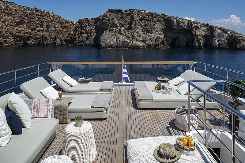 a deck with a view of the ocean and the mountains aboard DINAIA Yacht for Charter