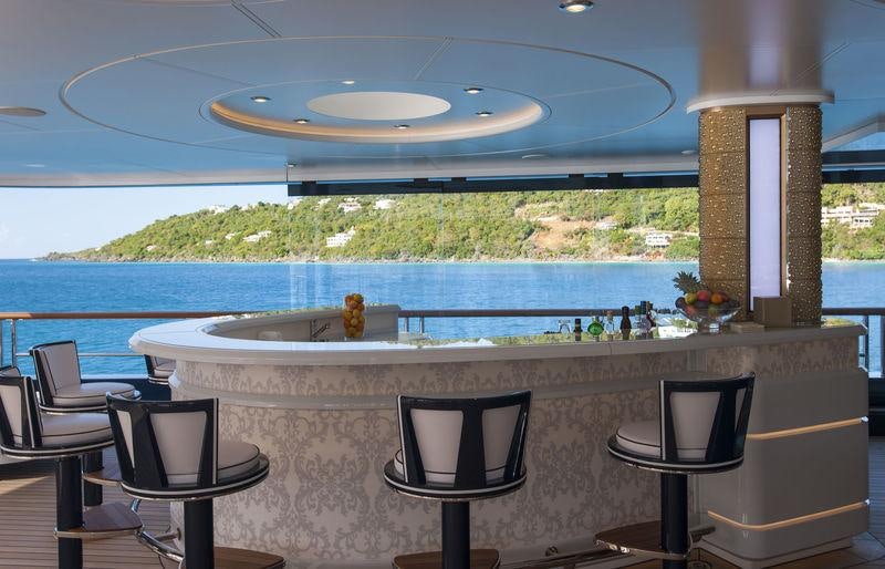 a large swimming pool with a large glass wall and a table and chairs aboard SOLANDGE Yacht for Charter